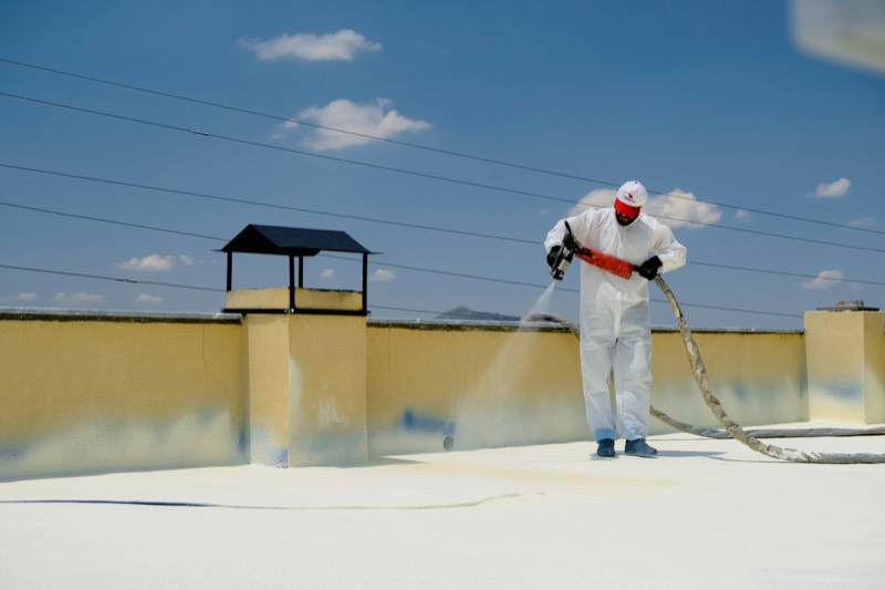 crew rolling a reflective coating onto a flat commercial roof
